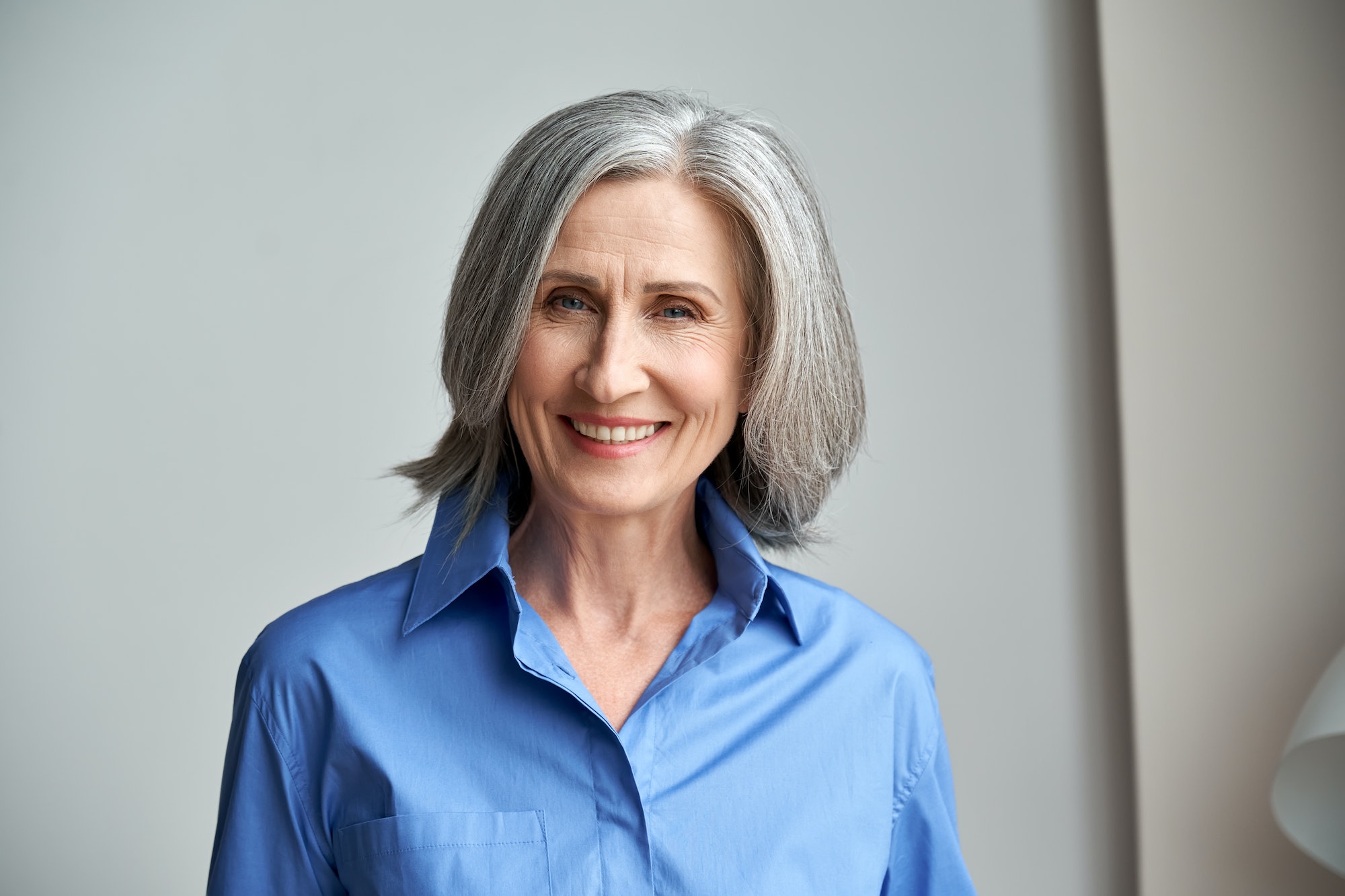 Smiling sophisticated mature grey-haired woman headshot portrait.